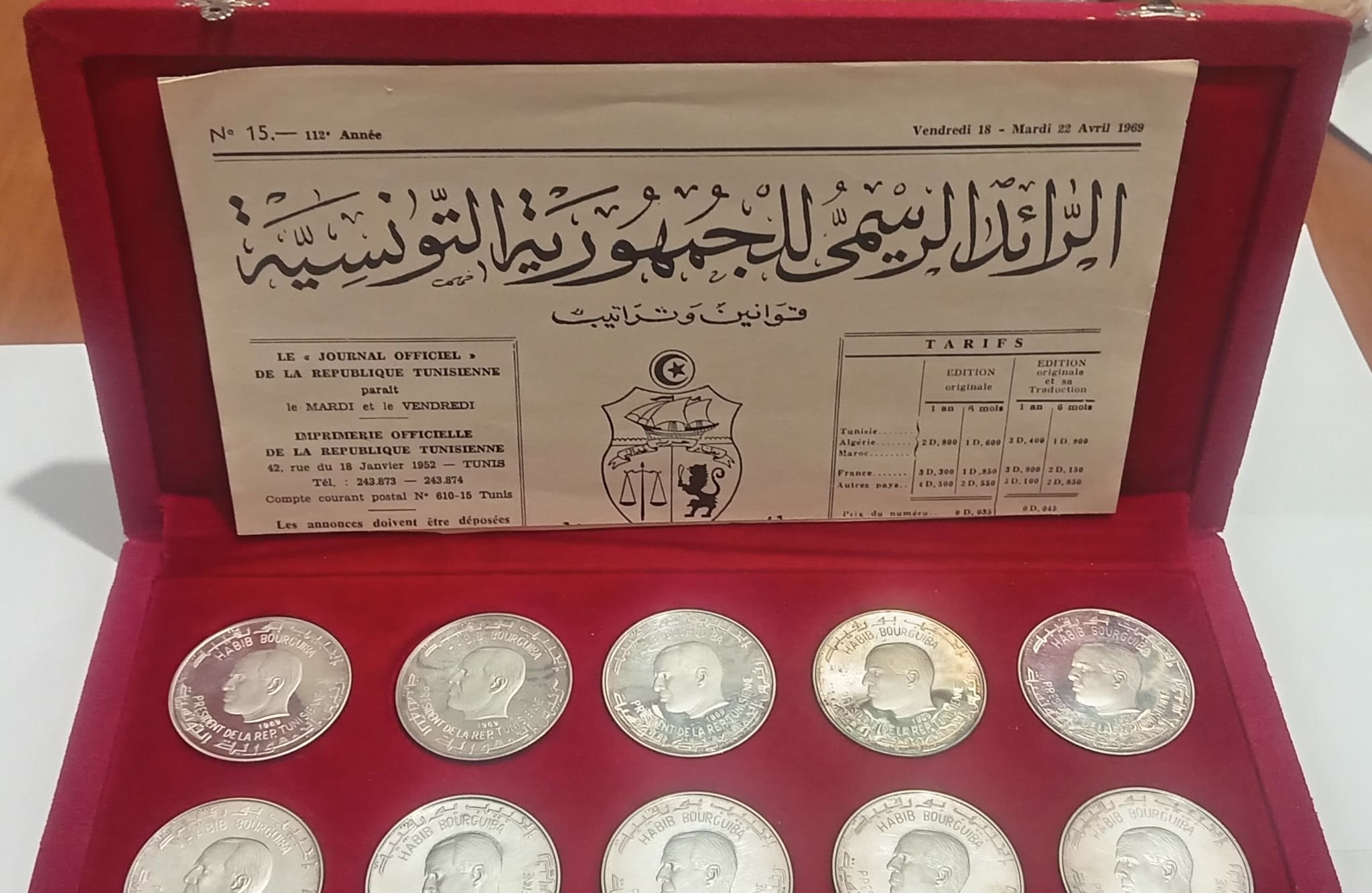 This set is a special collection of 10 commemorative silver coins issued by the Republic of Tunisia in 1969. The key features of the set include: Presentation Box: The coins are housed in a luxurious red velvet case embossed with the national emblem of Tunisia and the words République Tunisienne in Arabic and French. Coins: Each coin is made of 92.5% silver (sterling silver), with a face value of 1 Tunisian Dinar. The coins depict various significant historical and cultural themes of Tunisia, such as ancient architecture, maritime history, and notable figures. Certificate of Authenticity: A certificate accompanies the set, providing details about the coins, their silver purity, and the legal backing of the issuance. It refers to Presidential Decree No. 69-128 dated April 18, 1969. Official Journal Reference: The inside of the case includes a snippet from the Journal Officiel de la République Tunisienne (Official Gazette), further authenticating the set as a state-sanctioned commemorative issue. This set was likely produced to celebrate Tunisia's rich cultural and historical heritage, reflecting themes from antiquity to modern times. It serves both as a collectible item and a testament to the nation's identity in the post-independence era.